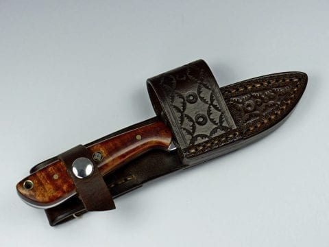 Brown handled knife inside handmade brown leather sheath