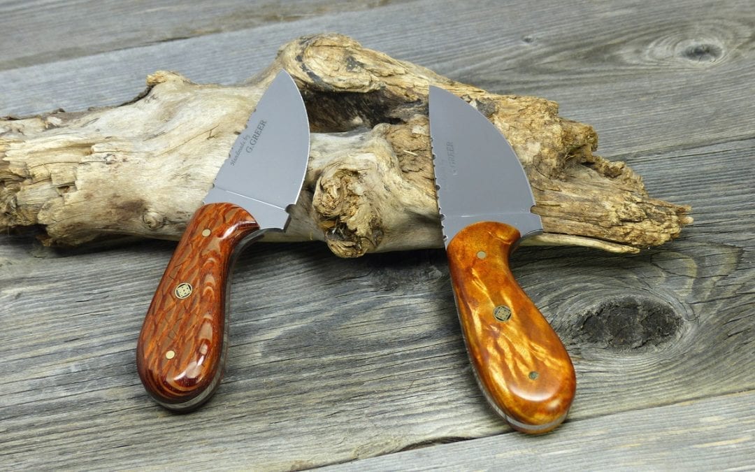 Two wood handled hunting knives resting on log